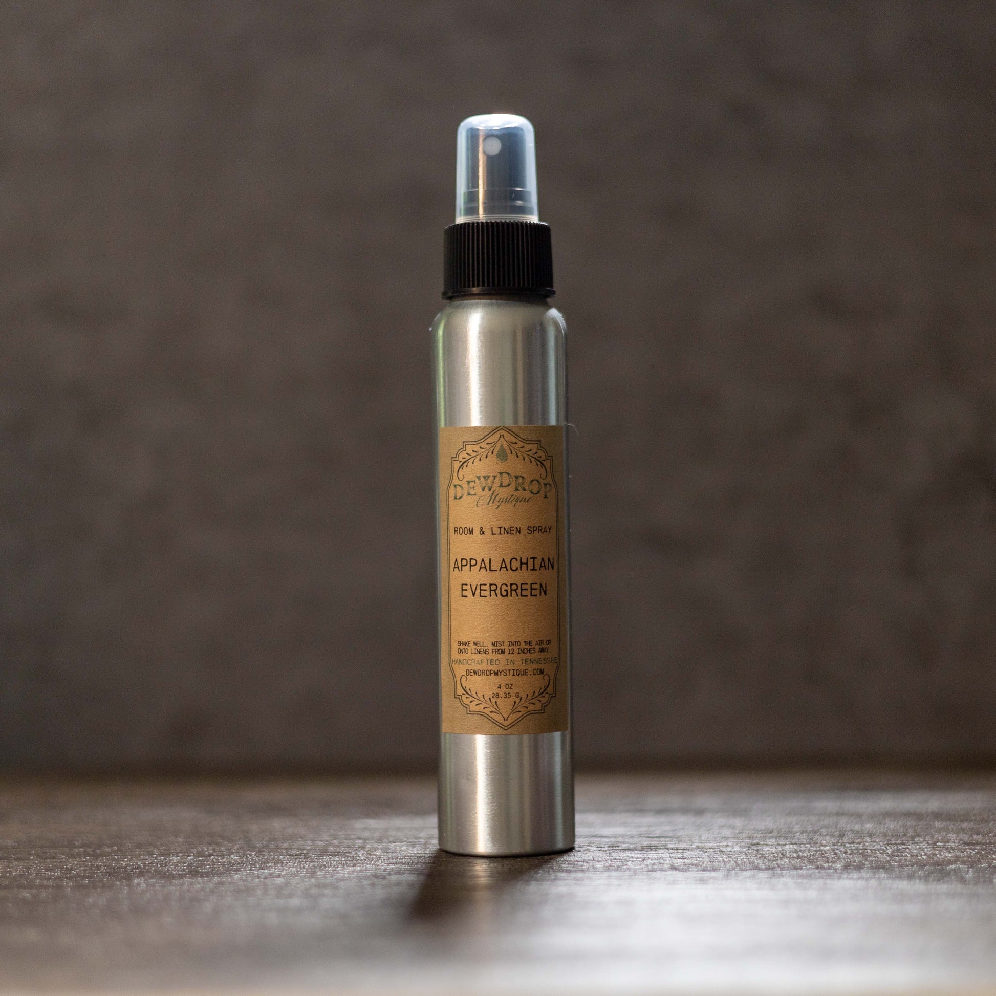 Metallic spray bottle with a brown label on a wooden surface