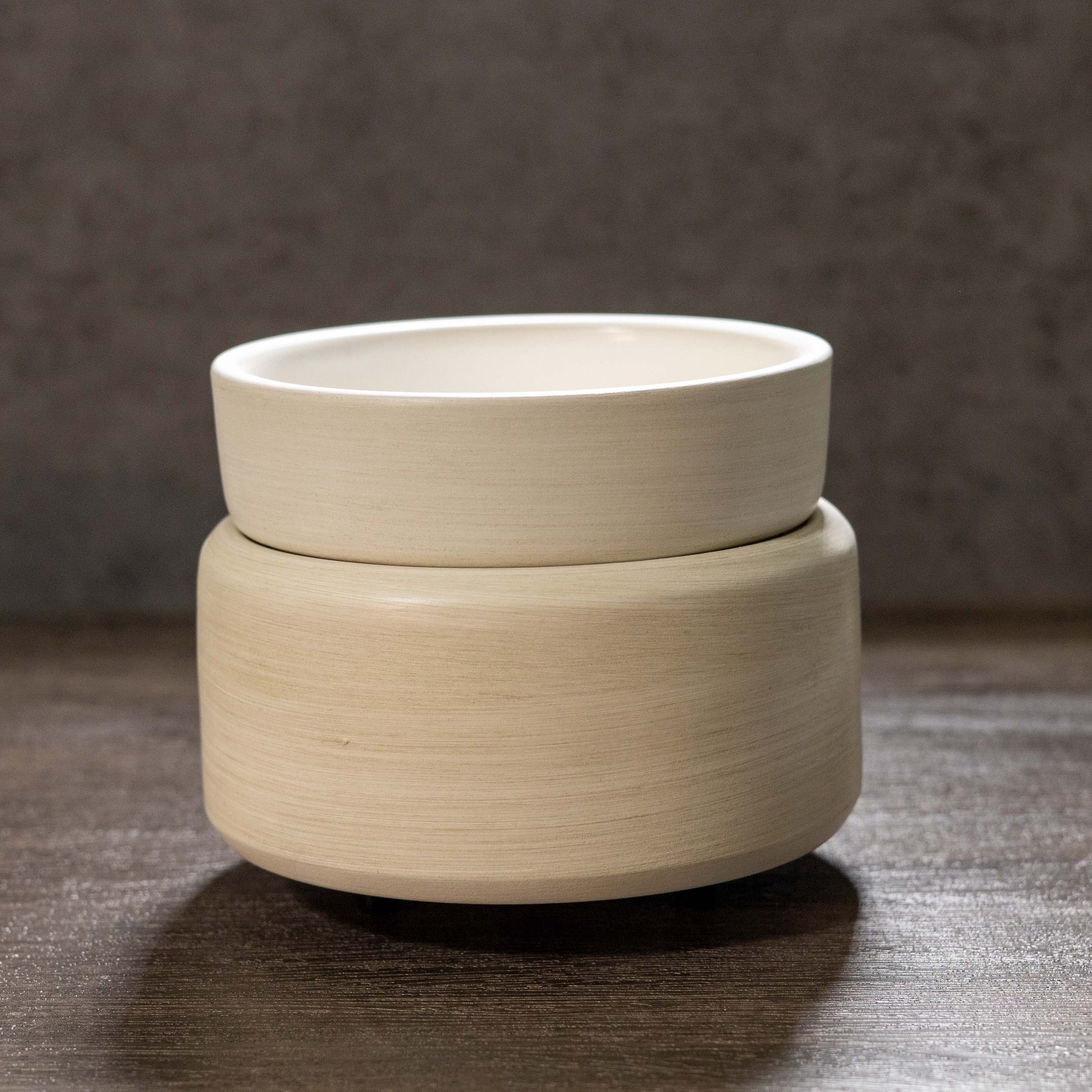 Stone ivory ceramic wax warmer on a textured surface with a neutral background