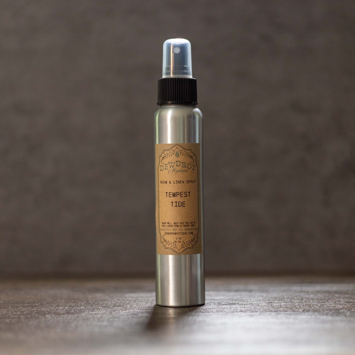 Metal spray bottle with a brown label on a wooden surface