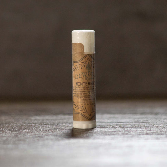 Balm stick with brown paper wrap on a wooden surface