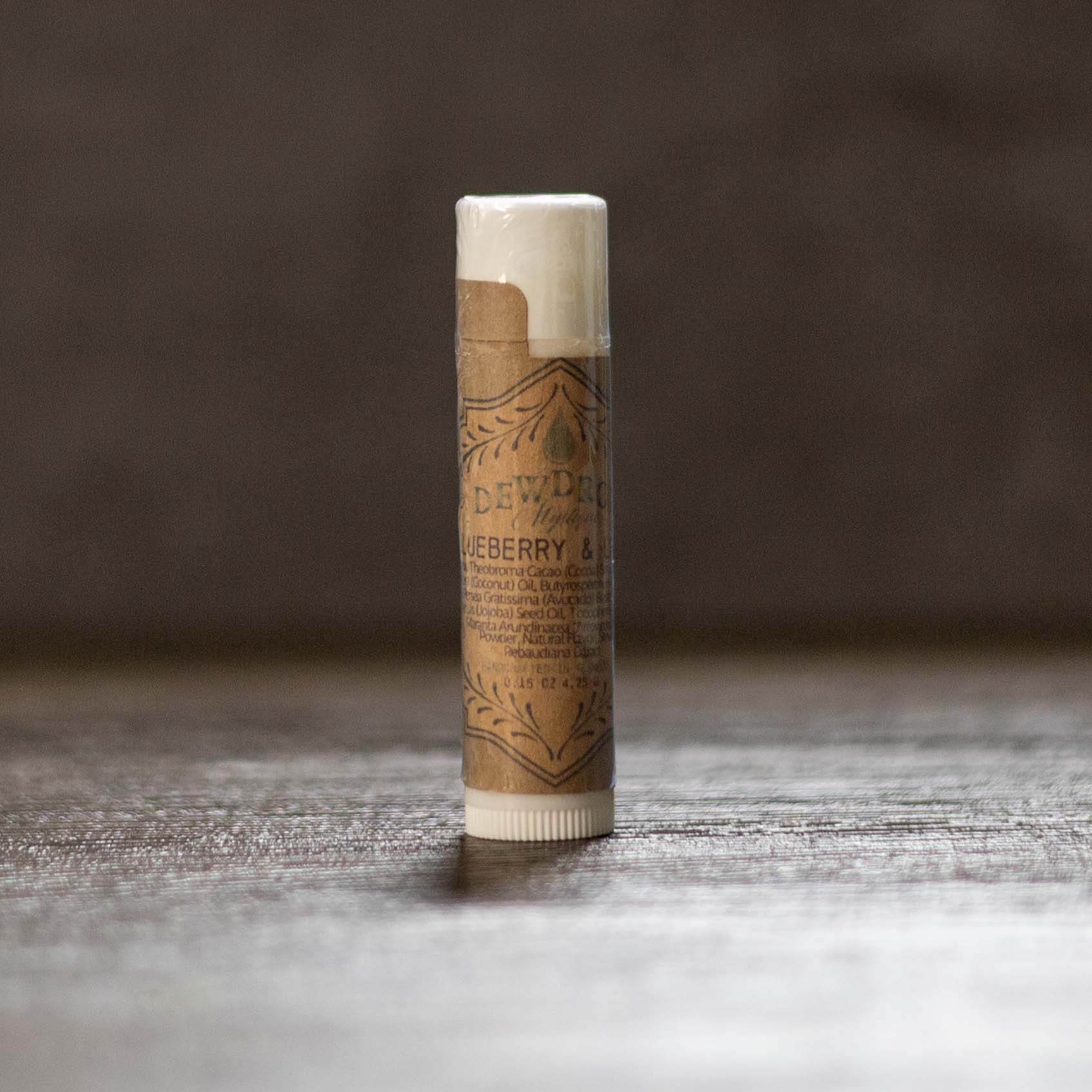 Balm stick with brown paper wrapper on a wooden surface