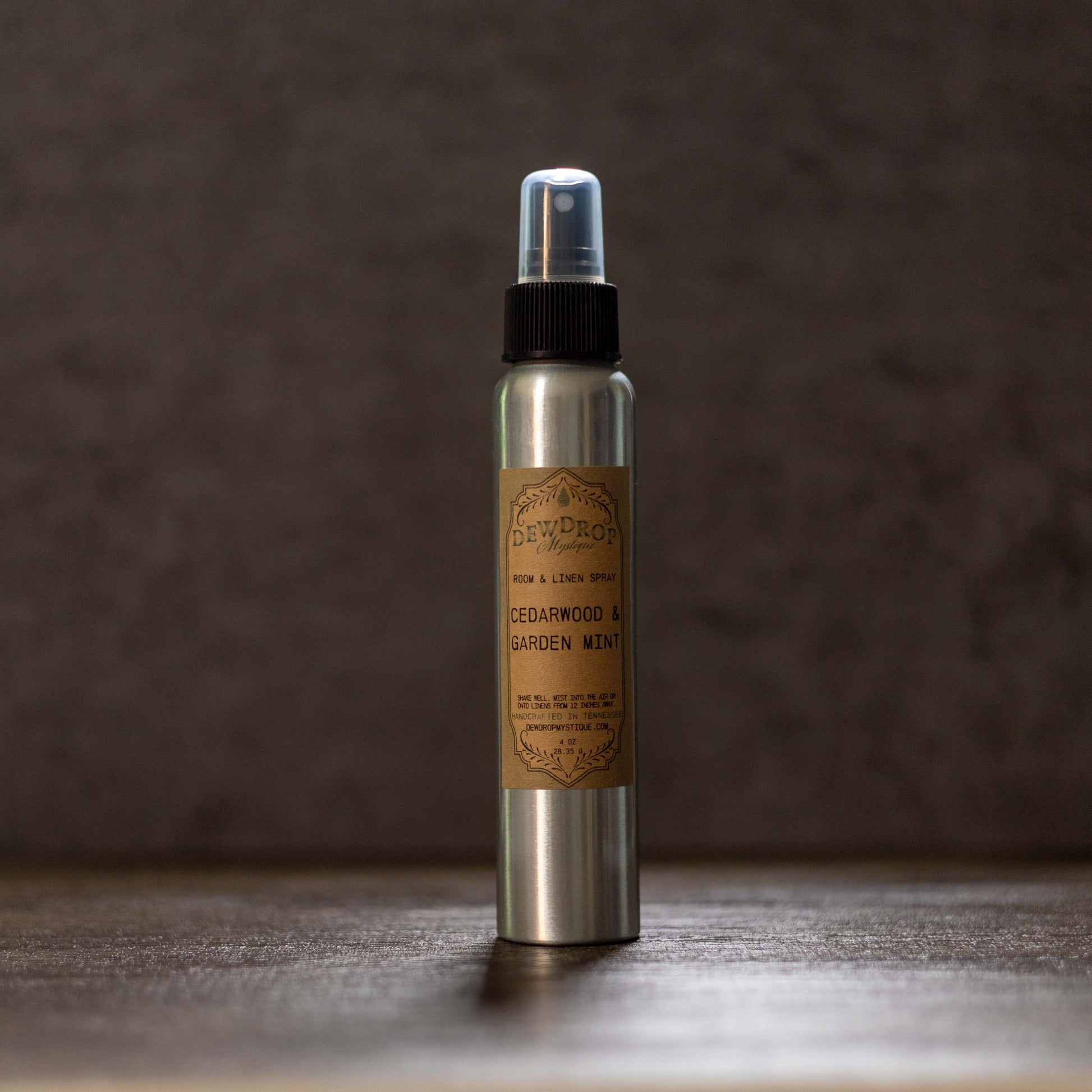 Metallic spray bottle with a label on a wooden surface and dark background