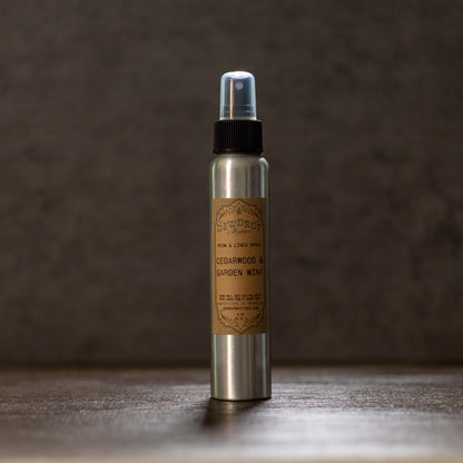 Metallic spray bottle with a label on a wooden surface and dark background