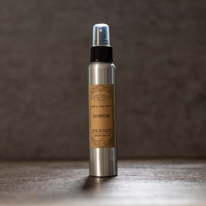 Metallic spray bottle with a brown label on a wooden surface and dark background