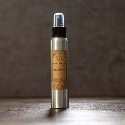 Silver spray bottle with a brown label on a wooden surface and dark background