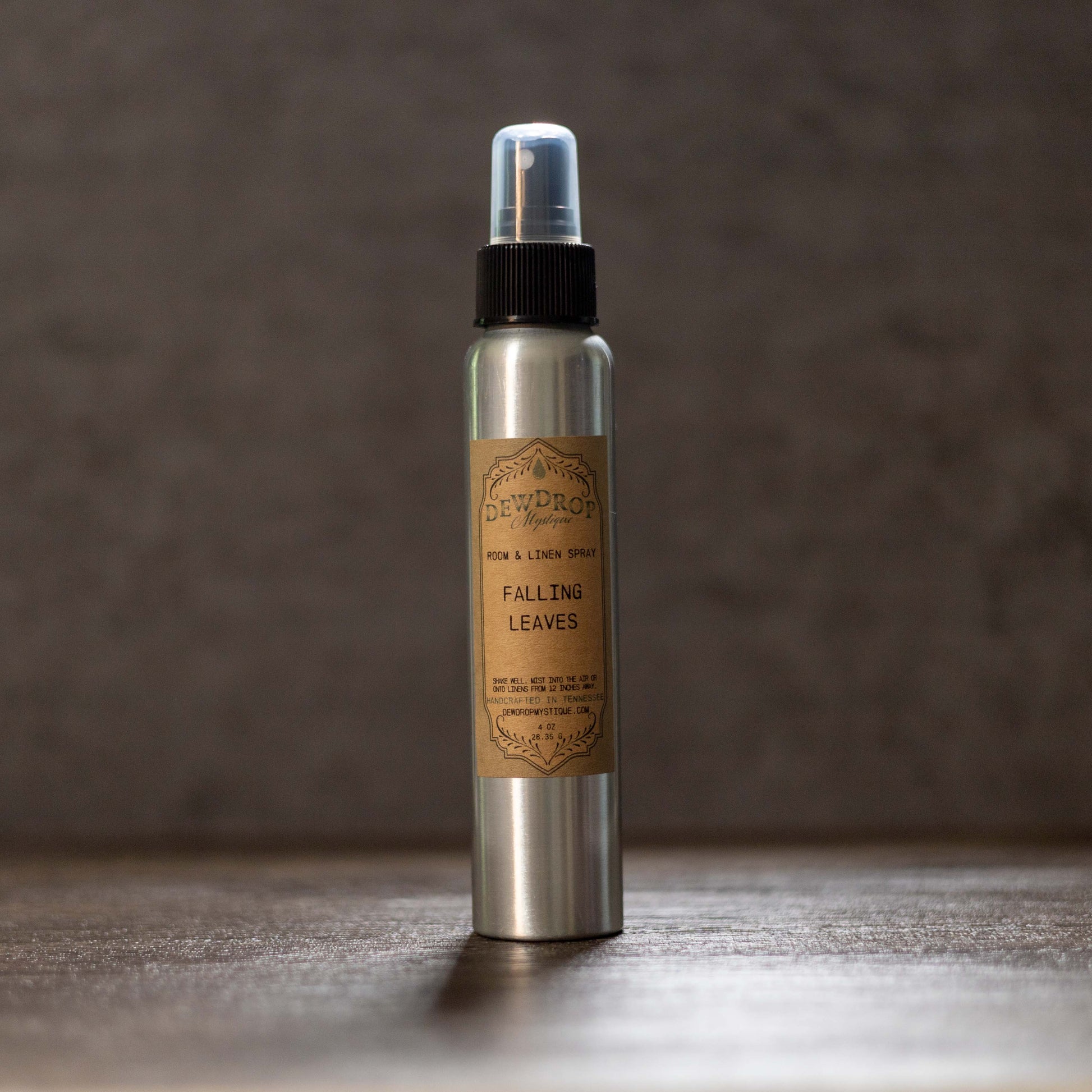 Silver spray bottle with a brown label on a wooden surface