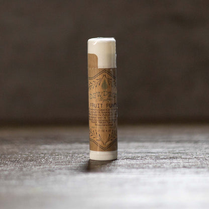 Fruit punch lip balm tube with a brown label on a wooden surface.