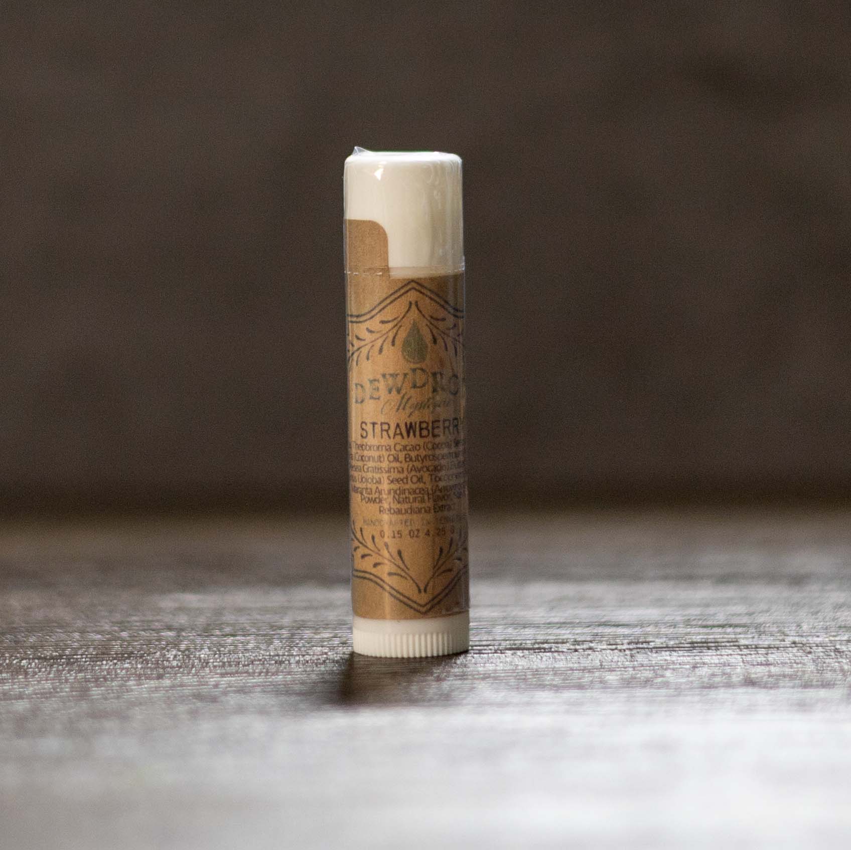 Tube of strawberry-flavored lip balm on a wooden surface with a dark background