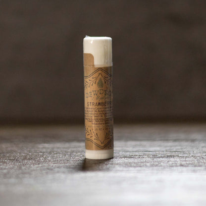 Tube of strawberry-flavored lip balm on a wooden surface with a dark background