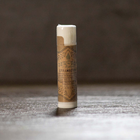 Tube of strawberry-flavored lip balm on a wooden surface with a dark background