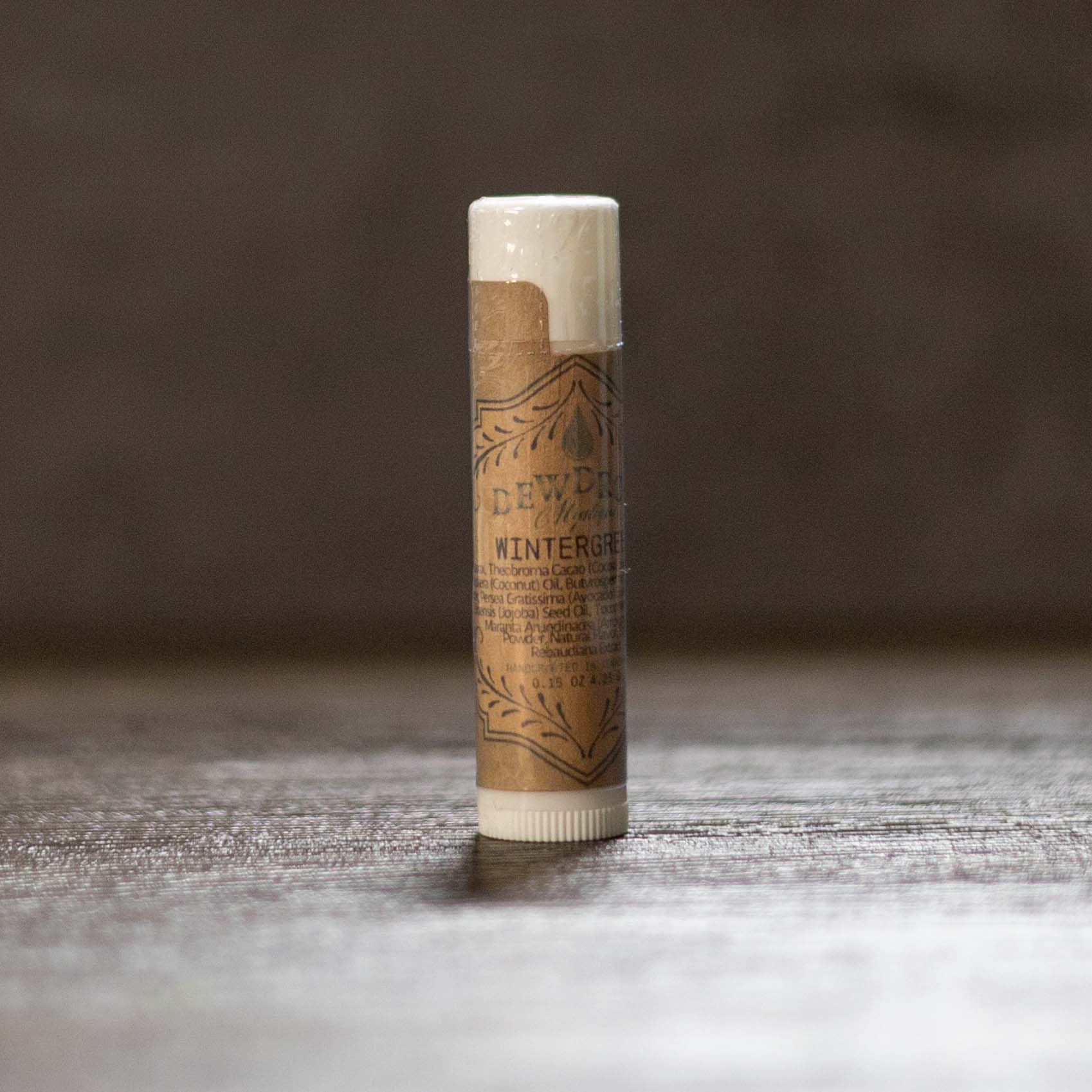 Balm stick with brown paper wrap on a wooden surface