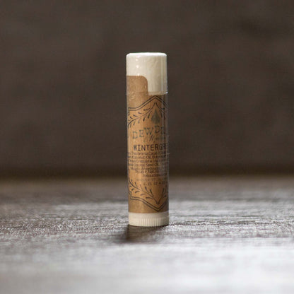 Balm stick with brown paper wrap on a wooden surface